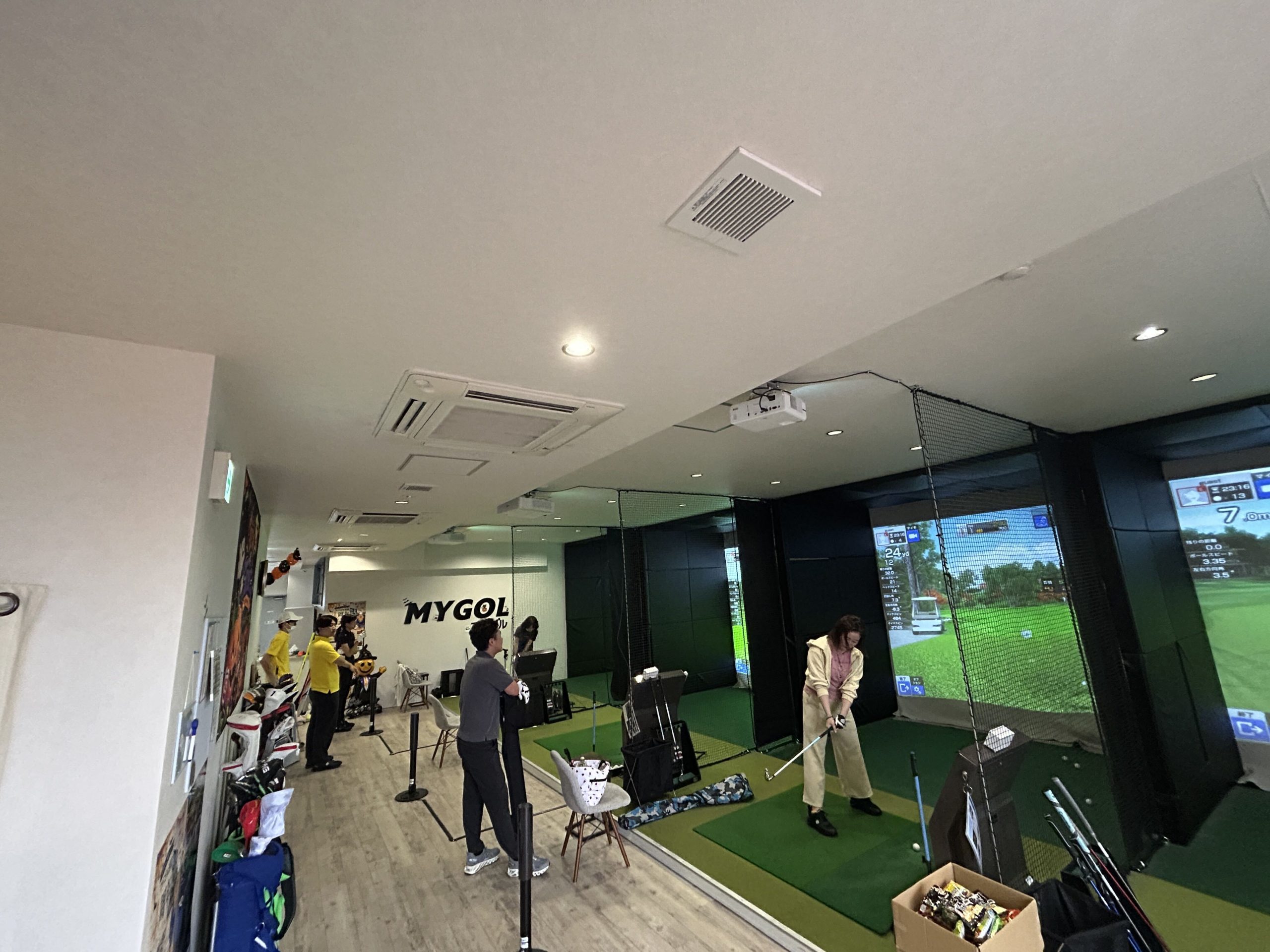 シミュレーターに向かってクラブを構える参加者と浅草店の打席